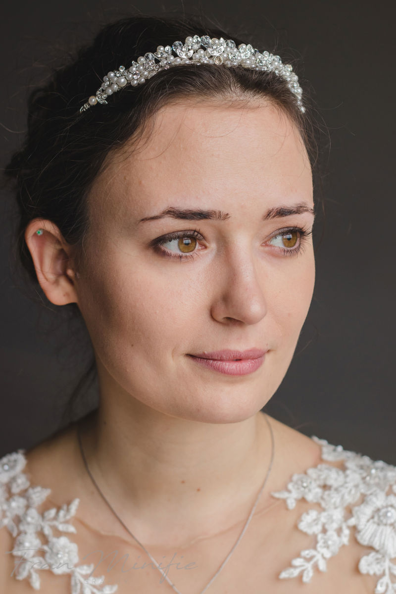 Bride standing by window in elegant lace-back gown