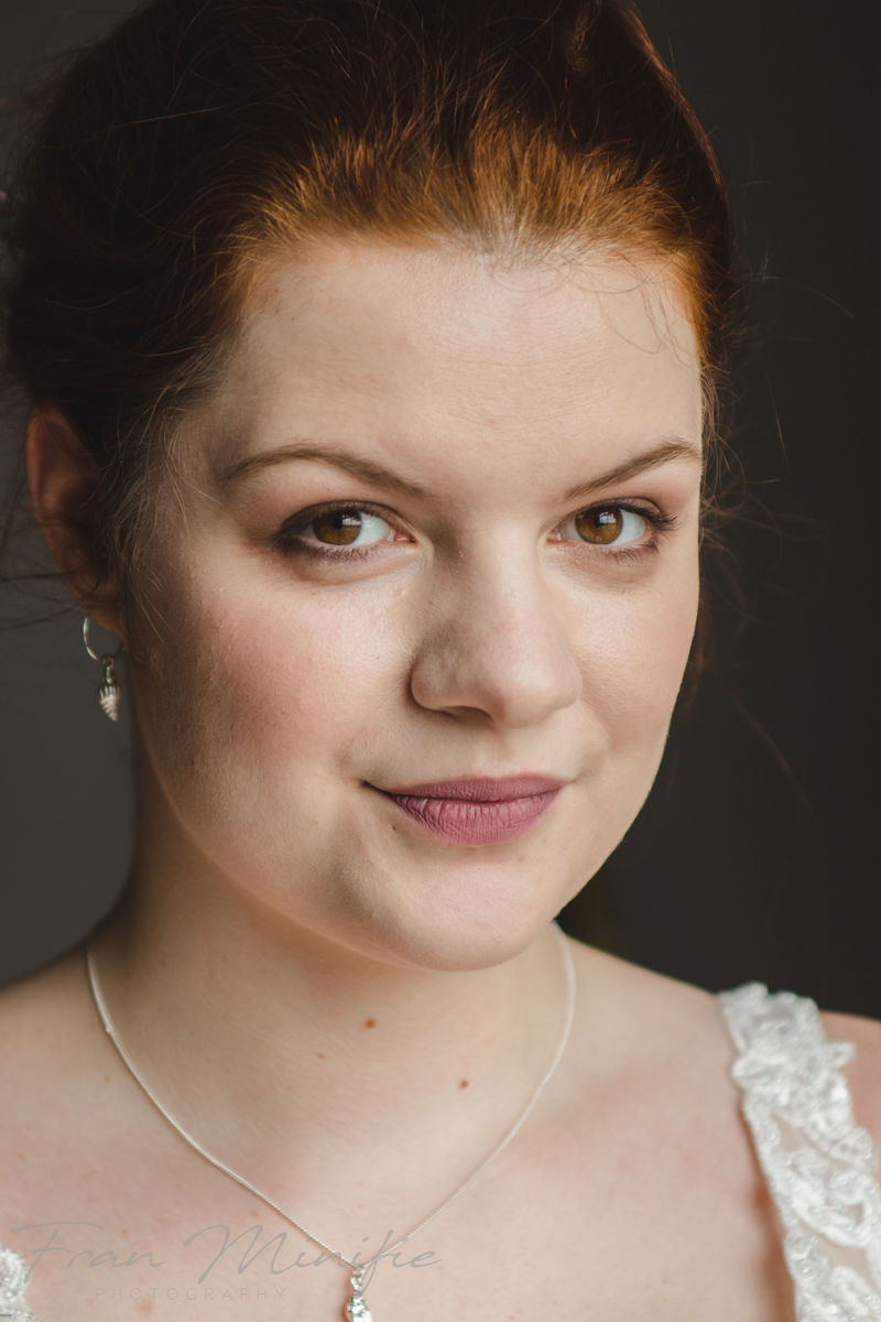 Auburn-haired bride with natural makeup and lace dress detail